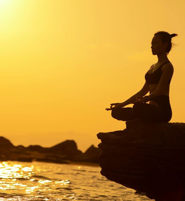 Silhouette of a person in a yoga warrior pose at sunset.